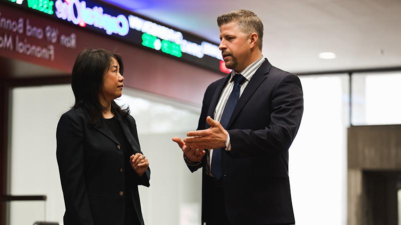 Two adults talking in front of financial markets lab